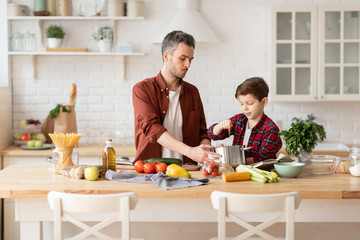 Father and son cooking diner for mother