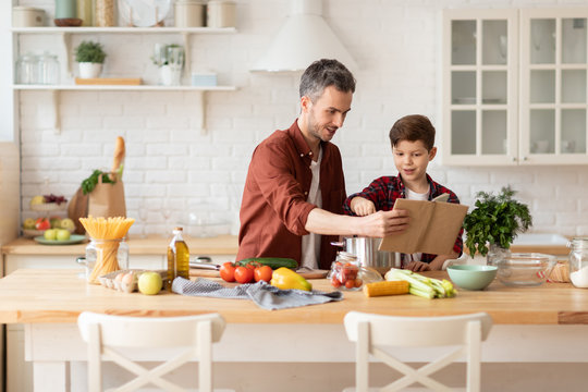 Son And Dad Reading Recipe Book And Cooking