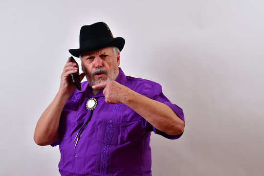 Serious Old Man Having A Conversation On His Smartphone.Dapper Old Man In A Serious Conversation On His Cellphone .Sharp Dressed Senior Man Speaking Over The Mobile Phone..