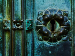 vintage, tarnished patina green copper plated door lock face detail. keyhole and surrounding...