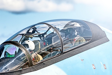 military pilot in fighter jet cockpit waving hand closeup against blue sky background. Fighter jet...