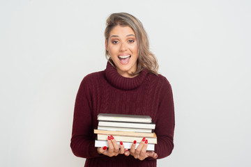 Excited young woman holding books. Beautiful cheerful young blonde woman holding pile of books and looking at camera. Education concept