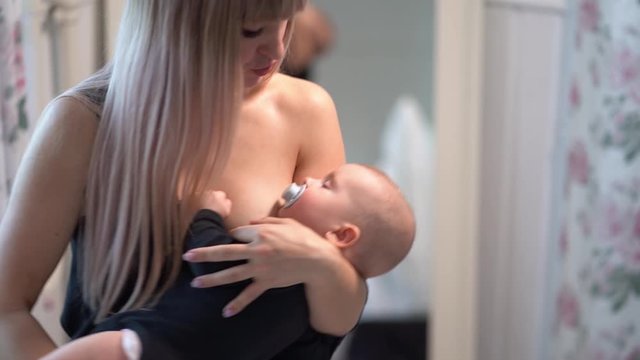 mom in black cradles baby with a pacifier in mouth