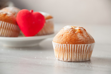 Fresh homemade delicious muffins on a plate with red hearts. Muffin closeup on a wooden table. Sweet dessert. Bon Appetit.