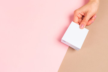 Obraz premium Beautiful young woman's hands holding jewelry box on pastel pink background.
