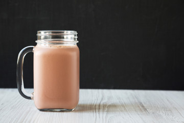 Homemade New England Chocolate Milkshake in a Glass Jar Mug, side view. Copy space.