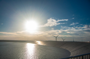 View of Lam Takhong Dam with wind turbines and blue sky. Clean energy concept.
