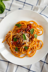 Homemade Bucatini all Amatriciana Pasta in a white plate on cloth, overhead view. Flat lay, from above, top view.