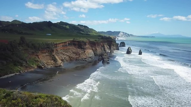 Aerial shot flying backward over cliff and ocean waves crashing coastline cliff, 4K, at the Elephant Rock and the three sisters in New Zealand