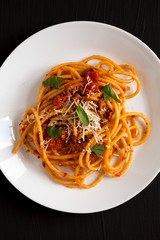 Tasty Homemade Bucatini all Amatriciana Pasta in a white plate on a black background, top view. Flat lay, overhead, from above.