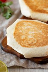 Tasty Homemade Beef Crunchwrap Quesadilla on a rustic wooden board, side view. Close-up.