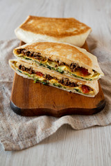 Tasty Homemade Beef Crunchwrap Quesadilla on a rustic wooden board, low angle view.