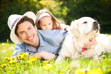 Fototapeta premium Happy family. Father with child and dog on a meadow.