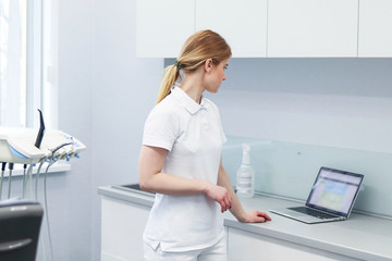 Woman dentist keeps a record of customers in her laptop