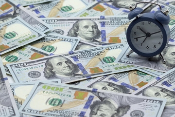 Time - money. Alarm clock on the stack of one hundred american dollars bills. Credit, deposit and mortgage concept.