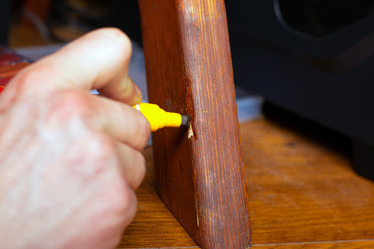 restoration and repair of wooden furniture the master hand closes the scratch with a special marker close-up