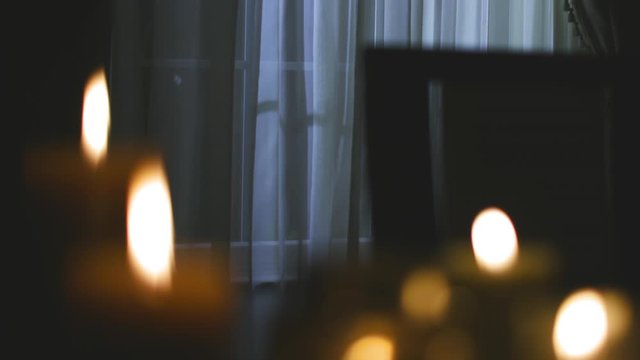 Rack focus on a group of candles illuminating a dark home during a power outage.