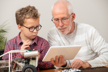 grandpa and son little boy repairing  model radio-controlled car at home