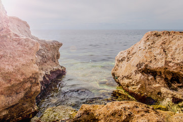 Fototapeta na wymiar Black Sea red rocks coastline. Cape Chersonesos wild beach in Sevastopol, Russia.