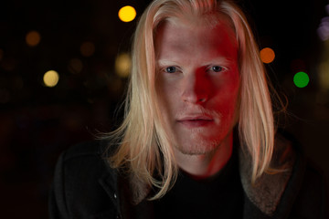 Albino man looking at the camera night city portrait - obrazy, fototapety, plakaty