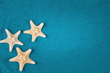 Fototapeta na wymiar Starfish on the blue sand copy space. Colored sand.