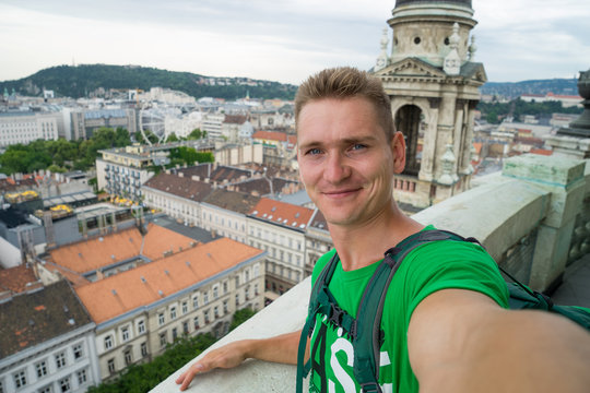 young attractive guy with blue eyes taking selfie on the top view point with Budapest on background