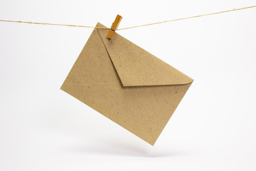 Blank cardboard envelope that hang on a rope with clothespins and isolated on white.