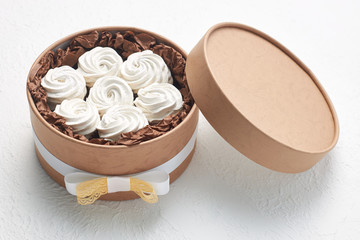 Delicious homemade zephyr packed in a brown round box on a white background