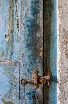 Puerta vieja azul desconchada con pestillo oxidado.