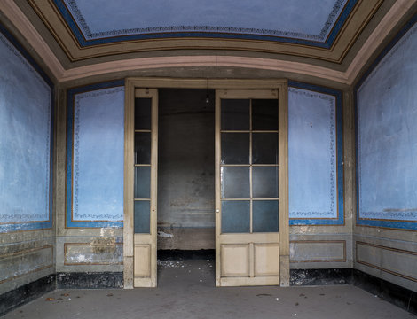 Puerta acristalada de entrada de habitaci&oacute;n azul con cenefas de casa abandonada.