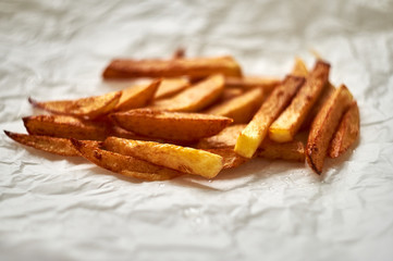 Tasty homemade potato french fries on white paper background