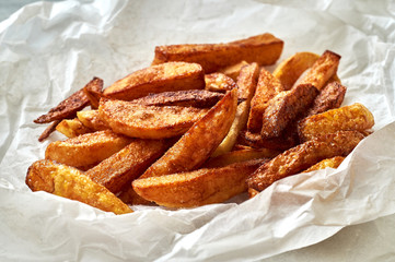 Tasty homemade potato french fries on white paper background