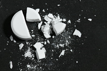 One broken white pill on black background macro photo - concept of medicine and medication treatment, health care