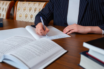 Girl writes an abstract in a notebook from a textbook