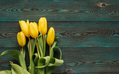  Yellow tulips on a blue wooden background copy space. Bouquet of yellow tulips flat lay.