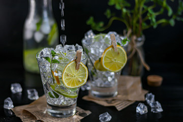 Refreshing summer alcoholic cocktail Margarita with crushed ice, lime and mint for decoration. Vodka splash. On a dark wooden background. On the leaves of the newspaper.