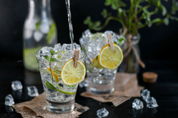 Refreshing summer alcoholic cocktail Margarita with crushed ice, lime and mint for decoration. Vodka splash. On a dark wooden background. On the leaves of the newspaper.