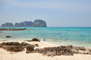 Several tourists swim in the sea on the beautiful beach of one of the islands of Thailand