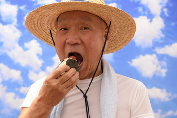 Fototapeta premium 青空でおにぎりを食べるシニア