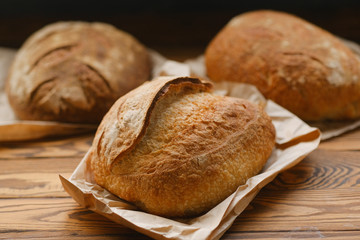 Assortment of baked bread on wooden table background. Bread background, top view of white, black and rye loaves. Healthy food. 