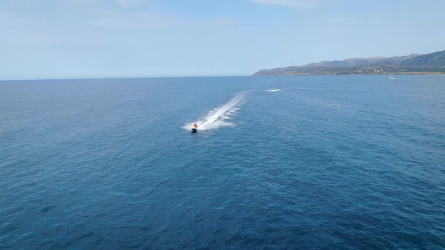 Jetski going fast on the water. Drone follow shot. Beautiful blue water. Malia, Crete, Greece