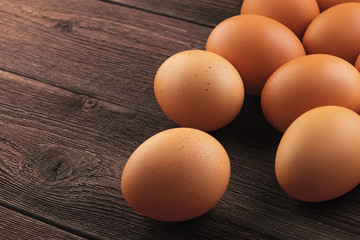 Closeup side view of a bunch of fresh brown chicken eggs with shallow depth of field on a vintage wooden rustic rural table with copy space