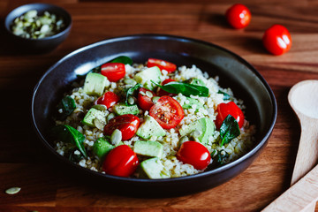 Healthy salad with bulgur, avocado, spinach and cherry tomatoes.