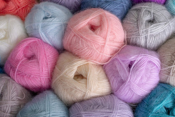 Close- up photo of many colorful rolls of knitting threads made of soft fluffy yarn. Skeins of woolen threads in pastel colors. Suitable for websites, online stores, catalogs