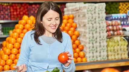 Woman as a customer buys fresh organic tomatoes