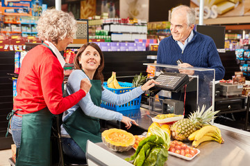 Employee helps young woman as a cashier trainee