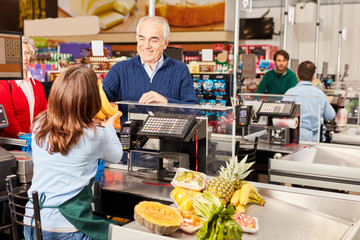 Customer at the supermarket cashier pays for fruit