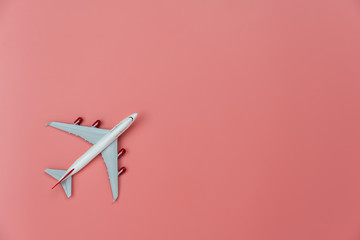 Table top view accessory of accessory travel in holiday background concept.Flat lay of white airplane on modern rustic pink paper at home studio office desk.copy space for creative design text.