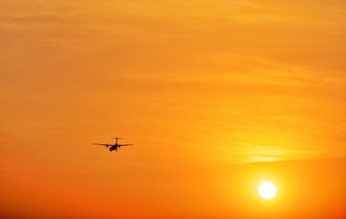 Fototapeta na wymiar Silhouette Turboprop Aircraft Flying Landing Against The Sun