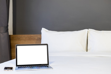 Laptop computer with blank screen with smart phone on white bed decoration in hotel bedroom interior background,Work and business in leisure with travel in the holiday concept.